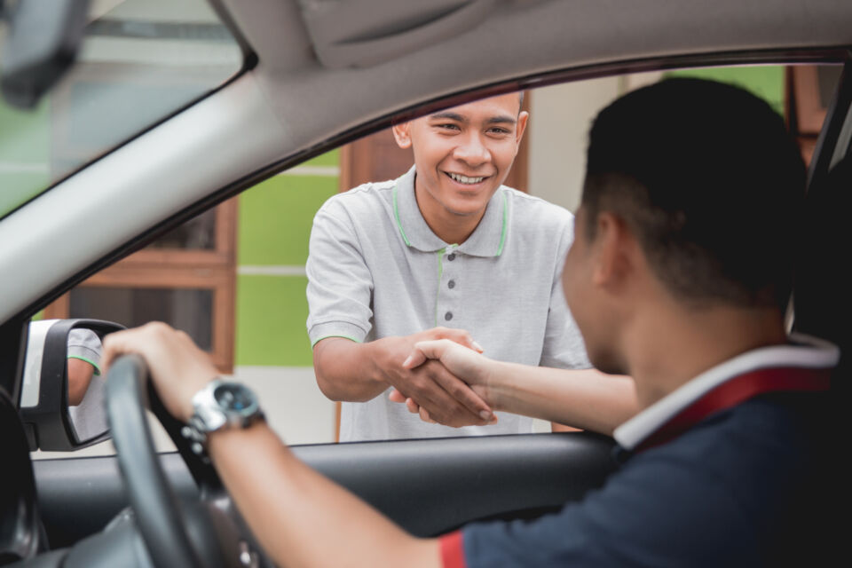 Car driver shaking hands with a pedestrian through passenger window